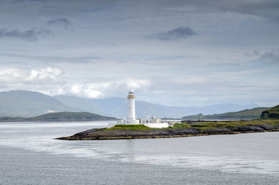 Lighthouse by sea against sky