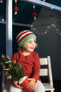 Smiling girl with christmas pot sitting on chair