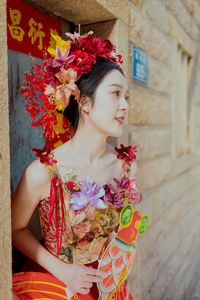 Portrait of young woman standing against wall