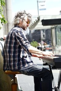 Side view of man sitting on seat in city