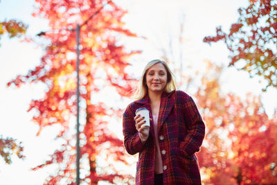 Portrait of smiling young woman standing on tree