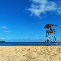 Lifeguard hut on beach against blue sky