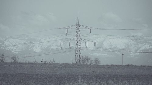 Electricity pylon on field against sky