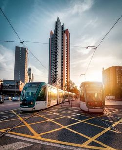 Cars on street by buildings against sky in city