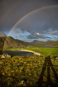 Scenic view of rainbow over landscape against sky