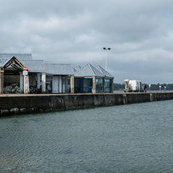 Stilt houses by sea against sky