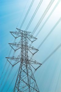 Low angle view of electricity pylon against blue sky