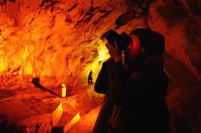 Woman photographing in illuminated cave at night