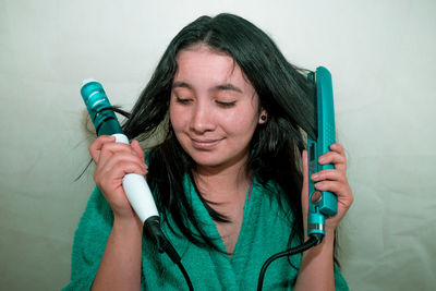 Close-up of young woman holding curling tongs and hair straightener