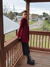 Full length portrait of young woman standing by railing