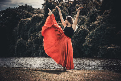 Rear view of woman with umbrella against trees