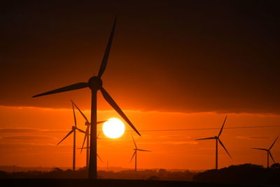 Silhouette windmill on field against sky during sunset