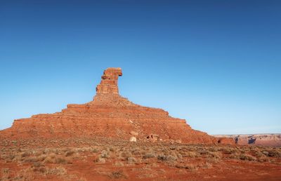 Orange and blue landscape and one triangular rock formation in valley of the gods in utah 