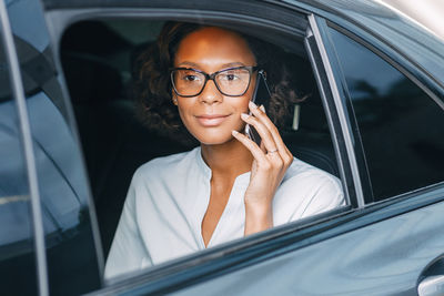 Young woman using mobile phone in car