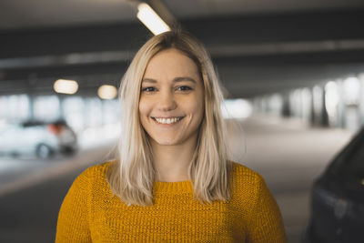 Portrait of smiling young woman standing in underground parking lot