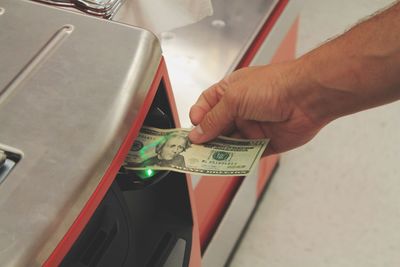 Cropped hand of man holding paper currency at atm machine