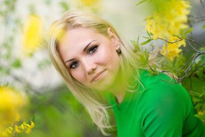 Close-up portrait of smiling young woman with yellow flower