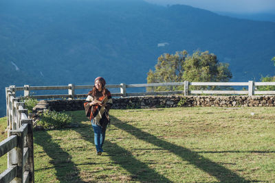 Woman standing by railing against mountain