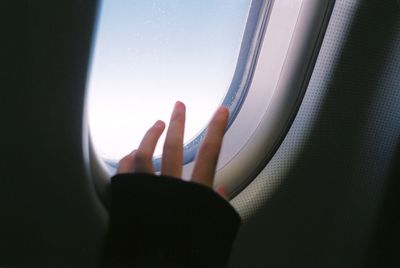 Cropped image of hand by airplane window 