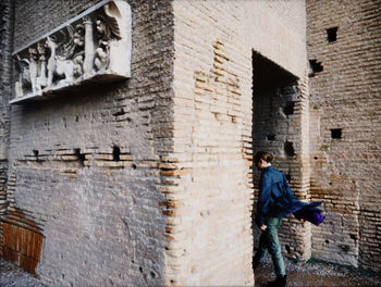 Man with umbrella on wall in alley against building