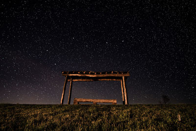 Low angle view of covered bench on hill with stars in background