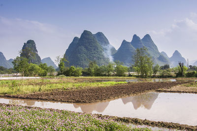 Scenic view of field by mountains against sky