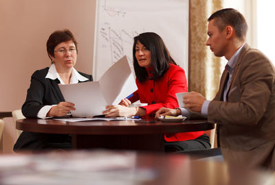 Smiling business colleagues working while sitting on table 