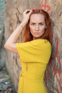 Portrait of woman standing by wall