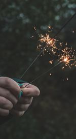 Cropped hands holding burning sparklers