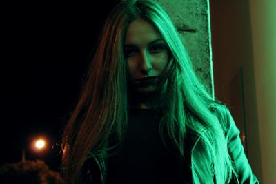 Close-up portrait of young woman against black background