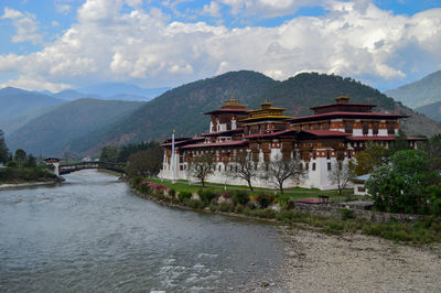 Bridge over river by buildings against sky