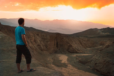 Man standing on mountain against sky during sunset