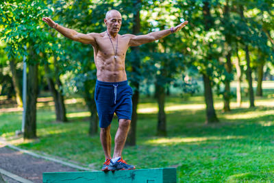 Full length of shirtless man exercising in park