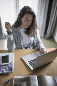 Woman using mobile phone while sitting on table