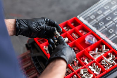 Crop of adult man in latex gloves examining instrument over tool box during work in modern workshop