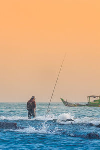 Man fishing in sea against sky