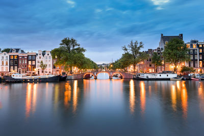 Buildings by river against sky at night