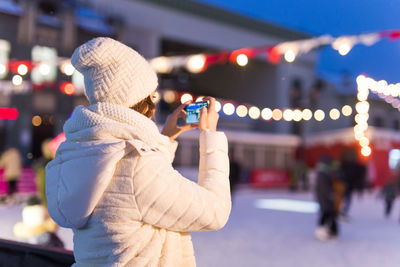 Woman holding umbrella in city during winter