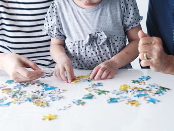 Midsection of family playing jigsaw puzzle