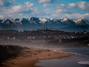 Scenic view of sea by snowcapped mountains against sky