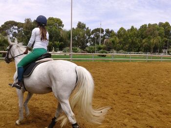 Woman riding horse at ranch against sky