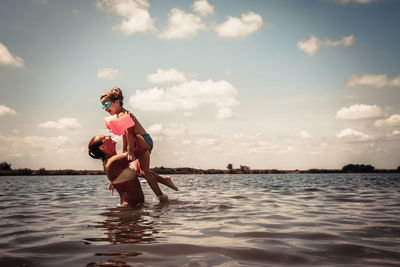 Cheerful mother and son having fun in the water in summer day.