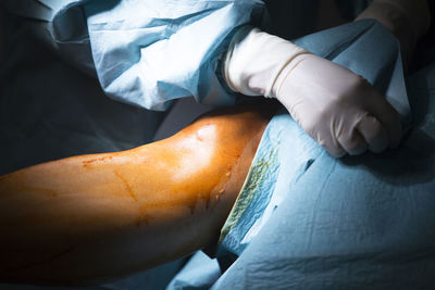 Midsection of doctor examining patient leg on hospital bed