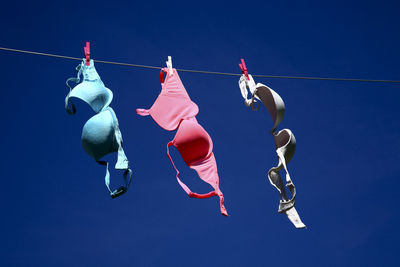 Low angle view of bras hanging on clothesline against clear blue sky