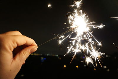 Close-up of hand holding firework display at night