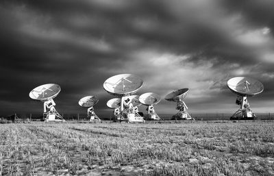 Satellite dish on land against cloudy sky