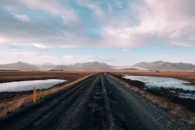 Diminishing perspective of empty road against cloudy sky