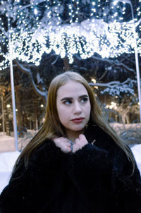 Young woman looking away while standing outdoors during winter
