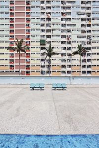 Empty benches on road against buildings in city during sunny day