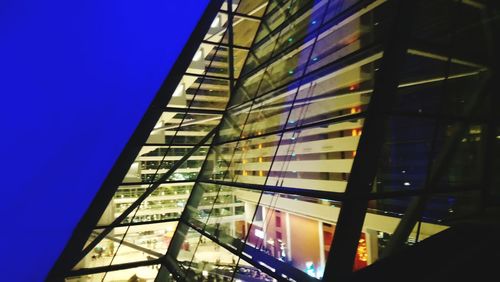 Low angle view of glass building against blue sky